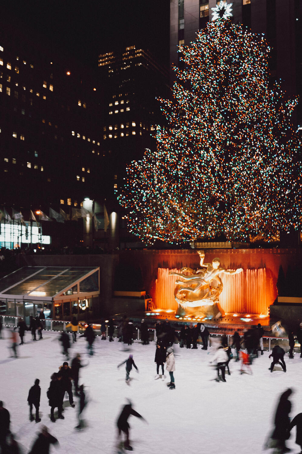 Rockefeller Christmas tree lit up at night with iceskating rink in the front